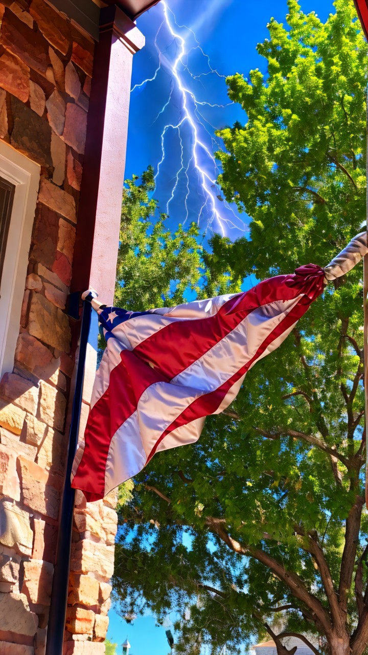 American flag against green leaves and blue sky