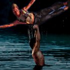 Male Acrobats Performing Dramatic Lift Above Water