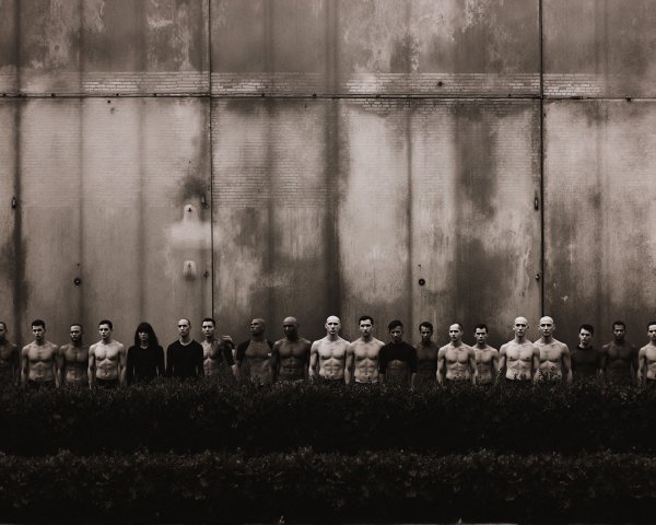 Black-and-white photo of individuals against industrial backdrop