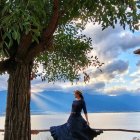 Serene landscape with a woman under a large tree