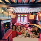 Women Toasting at a Wooden Dining Table by a Fireplace