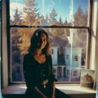 Young woman in dark green dress by large window