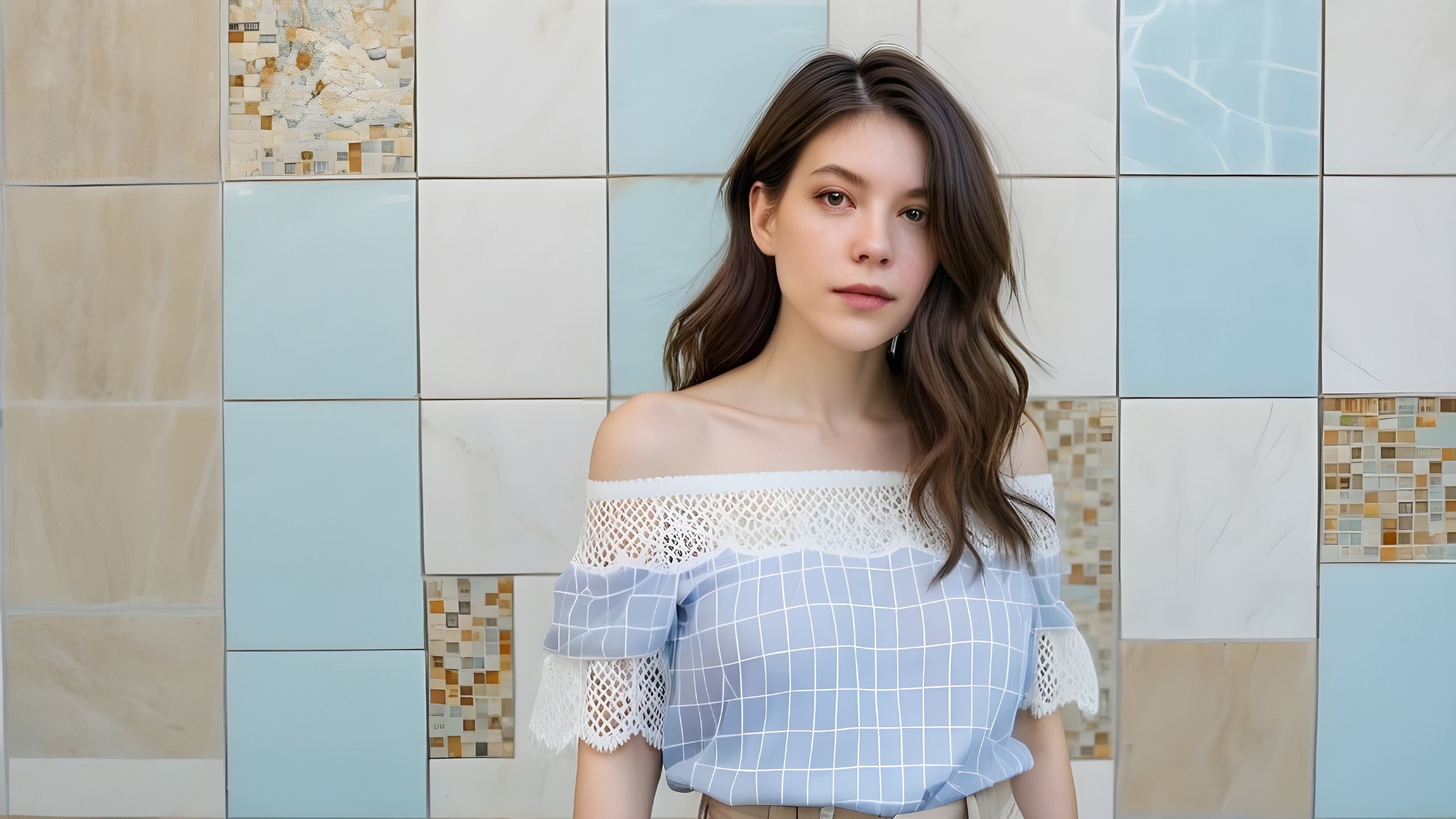 Young woman in off-shoulder blouse by tiled wall