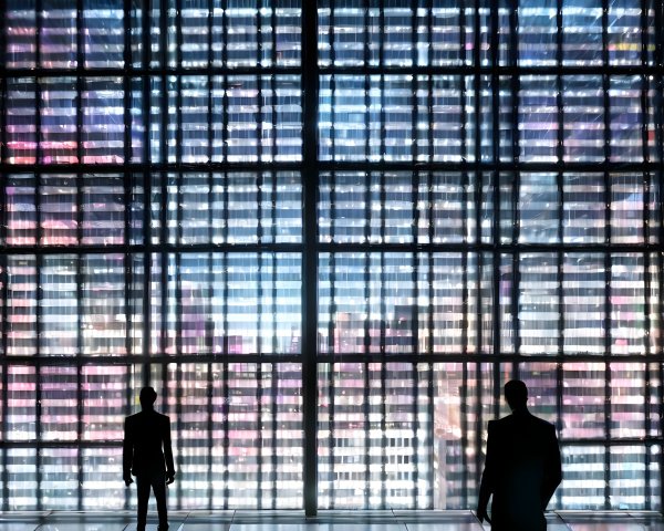 Silhouetted Figures Before Illuminated Cityscape Glass Wall