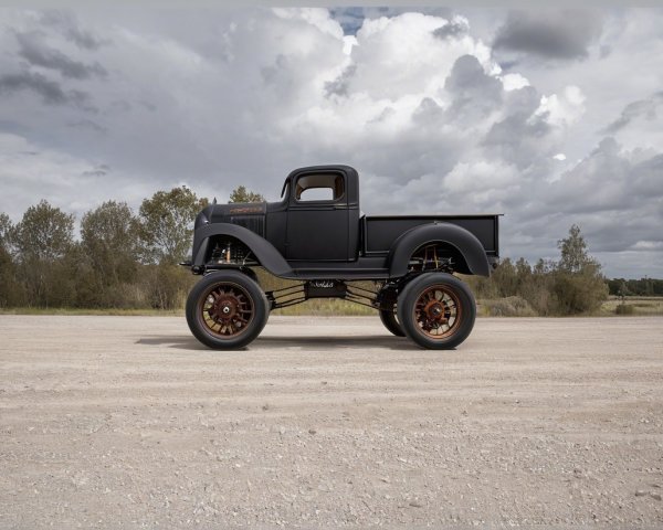 Vintage truck on dirt road with lush greenery backdrop