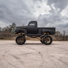 Vintage truck on dirt road with lush greenery backdrop