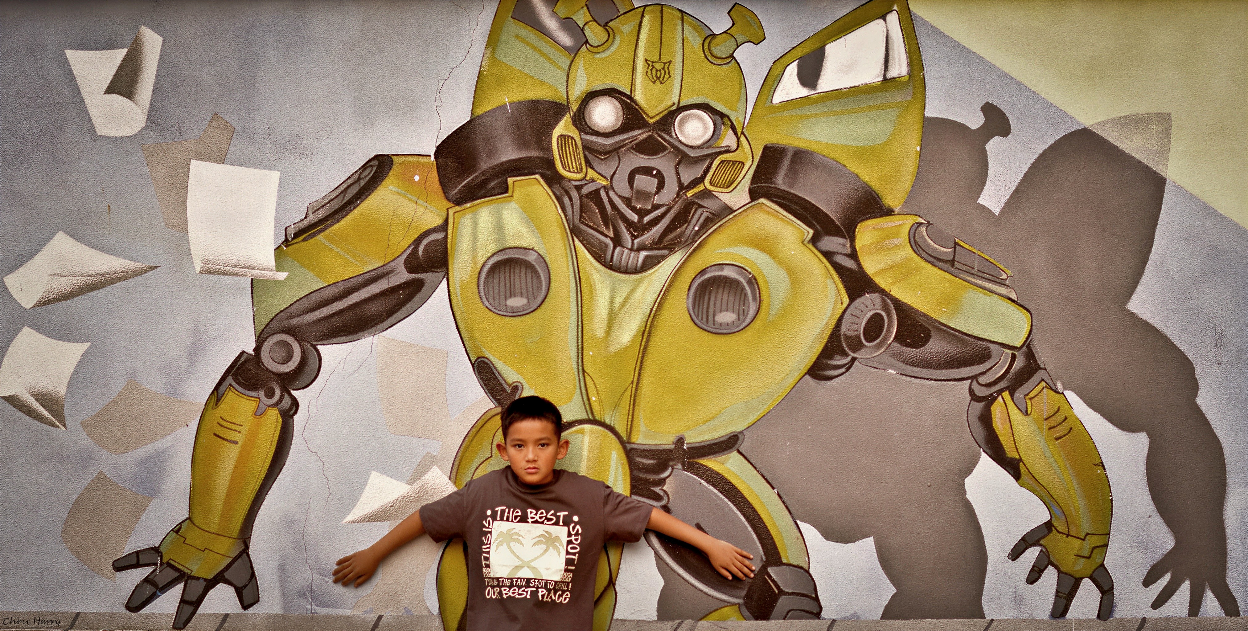 Boy in front of glowing robot graffiti on concrete wall