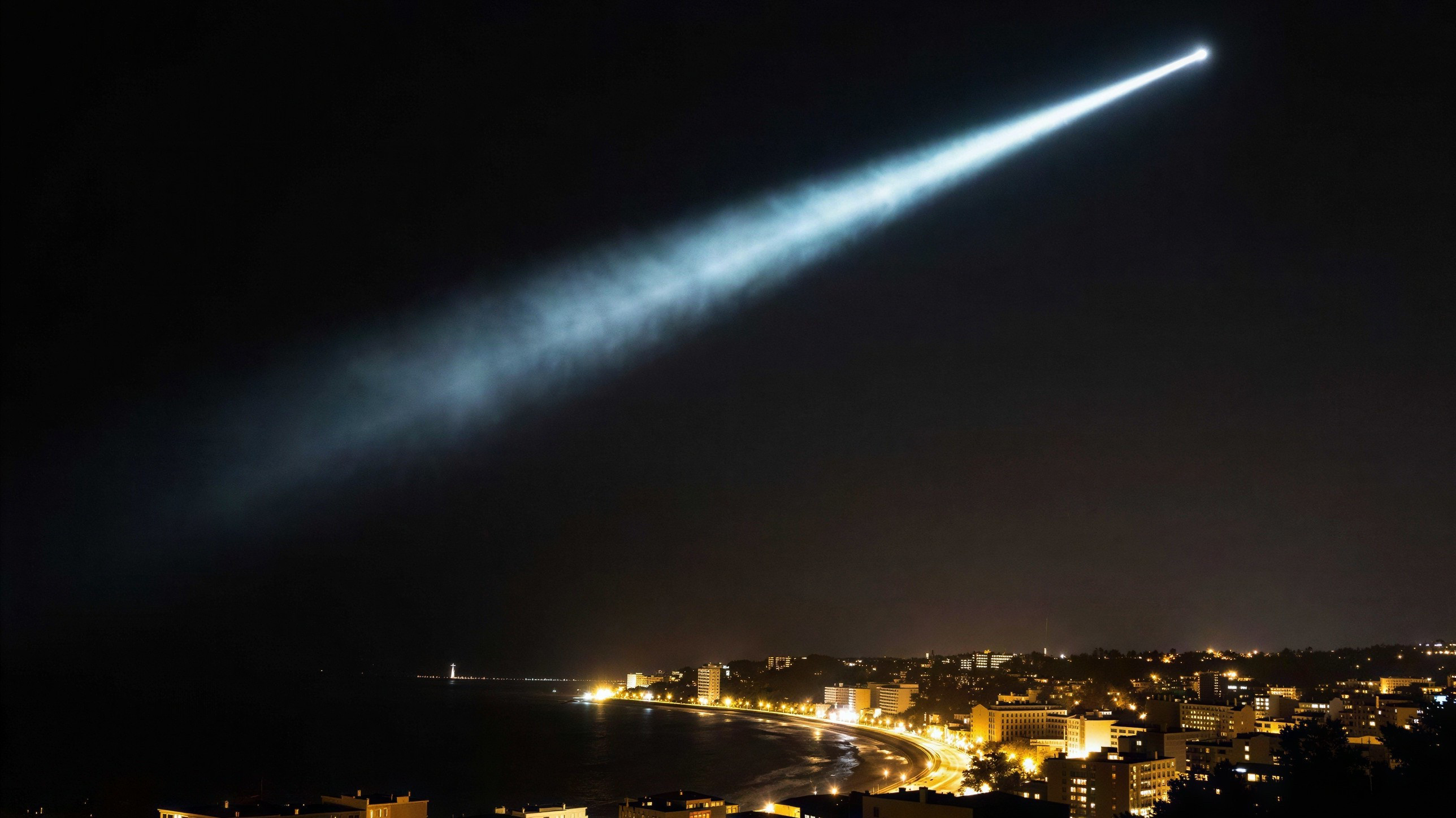 Aerial Night View of Coastal City with Spotlight Beam