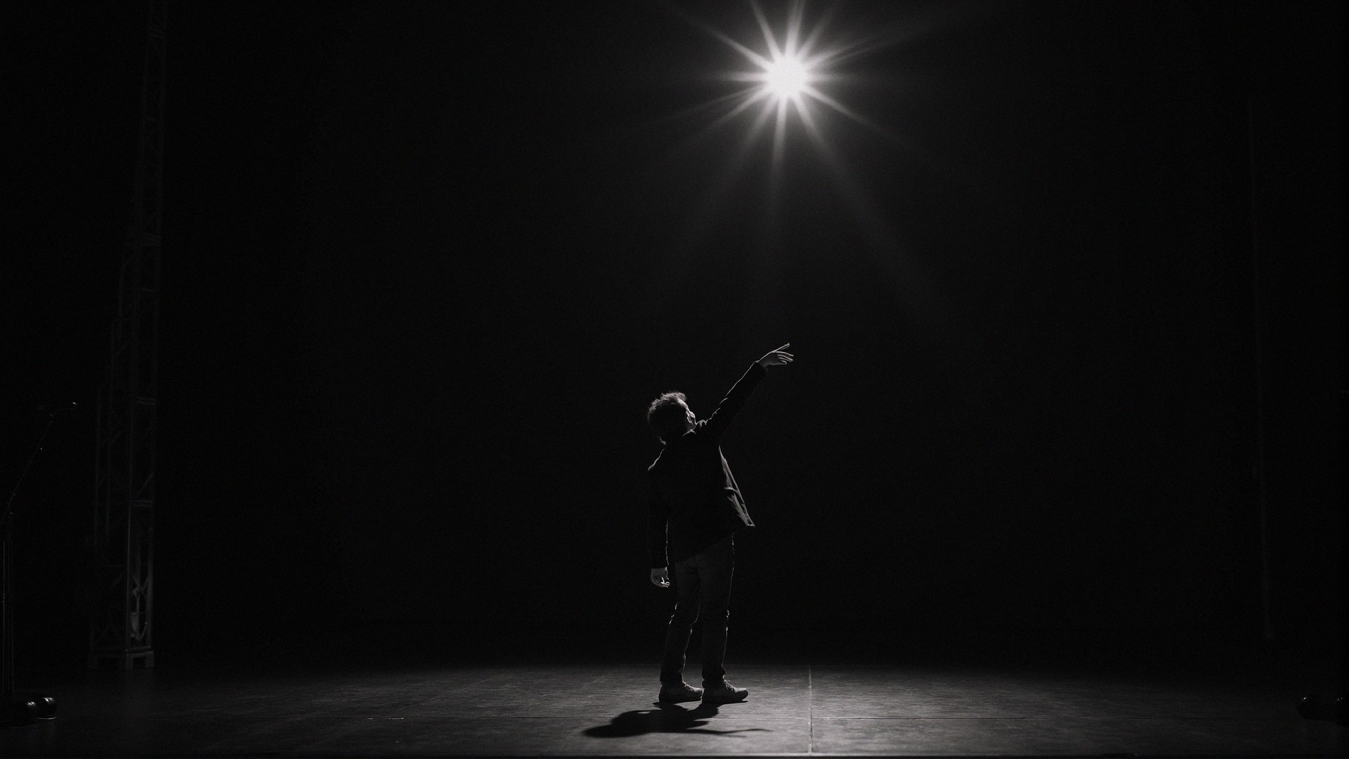 Silhouetted Figure on Dimly Lit Stage with Spotlight