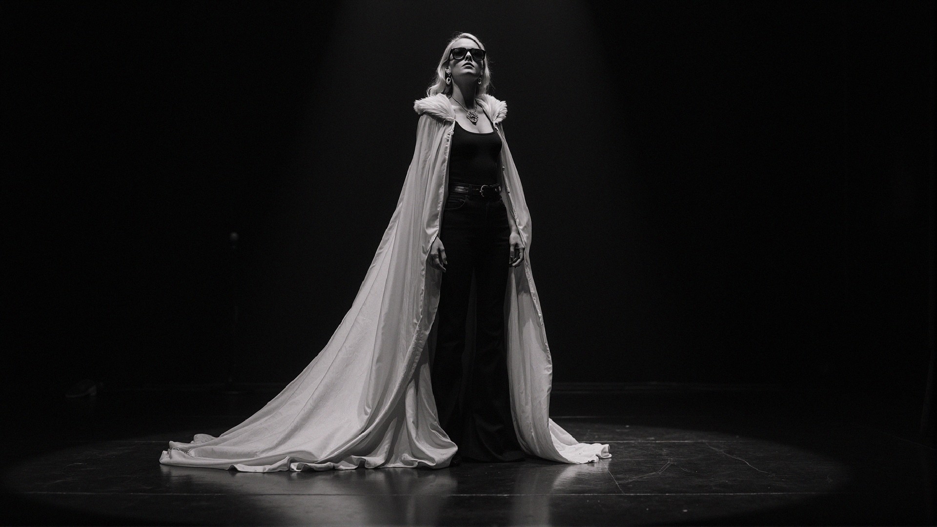 Dramatic Figure in White Cape on Dimly Lit Stage