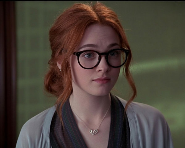 Young woman with red hair and large black glasses