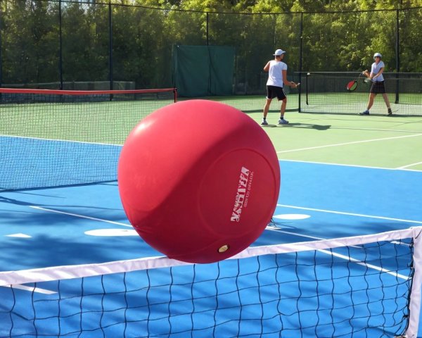 Oversized Red Ball Above Tennis Court with Players