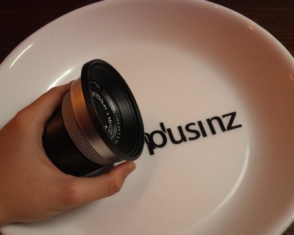 Camera Lens and Modern Logo on White Plate