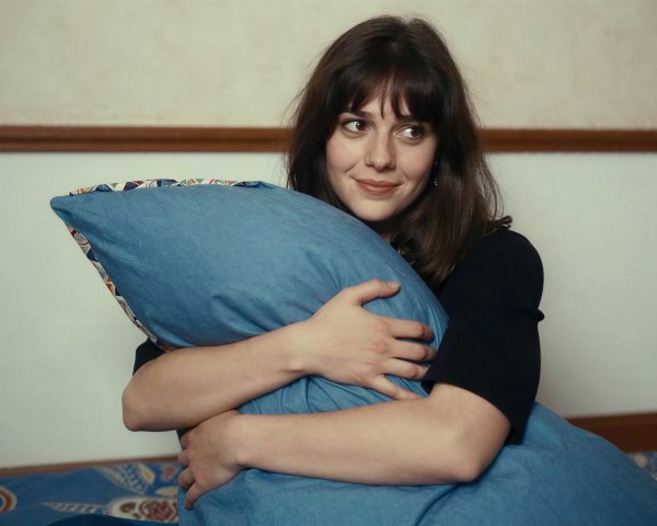 Young woman with dark hair holding a blue pillow