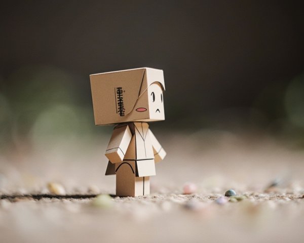 Animated Cardboard Figure on Textured Surface with Pebbles