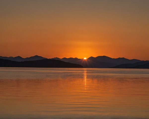 Serene sunset over a tranquil lake with mountains