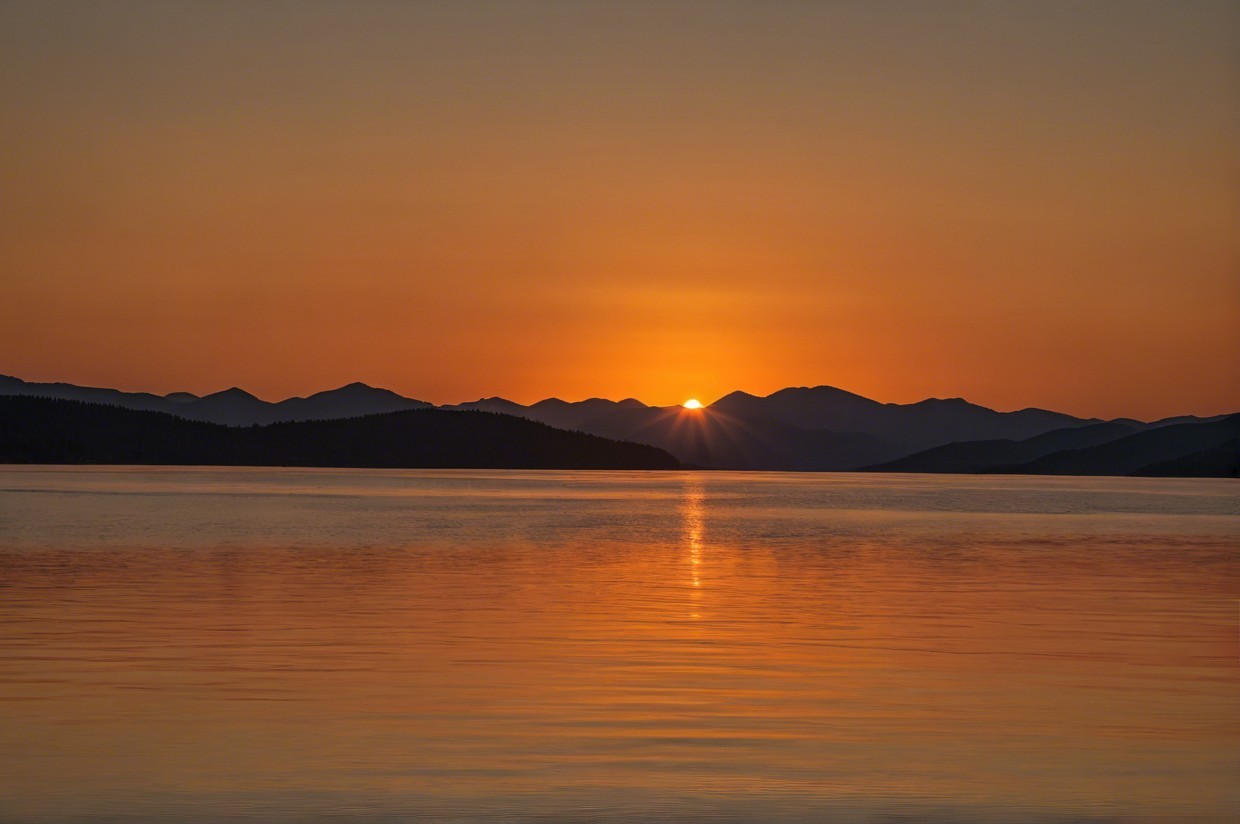 Serene sunset over a tranquil lake with mountains