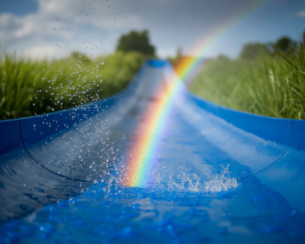 Vibrant Blue Waterslide in Lush Green Landscape