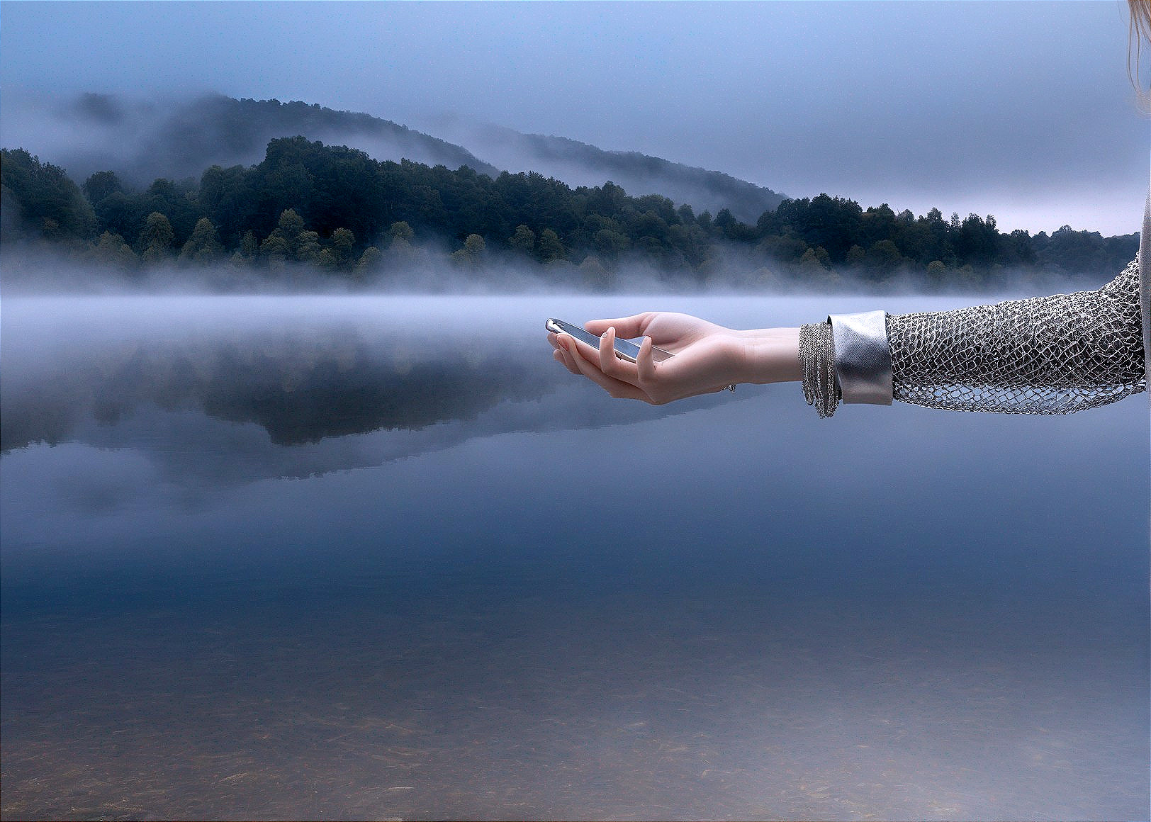 Hand above calm lake with misty treed hills and blue sky