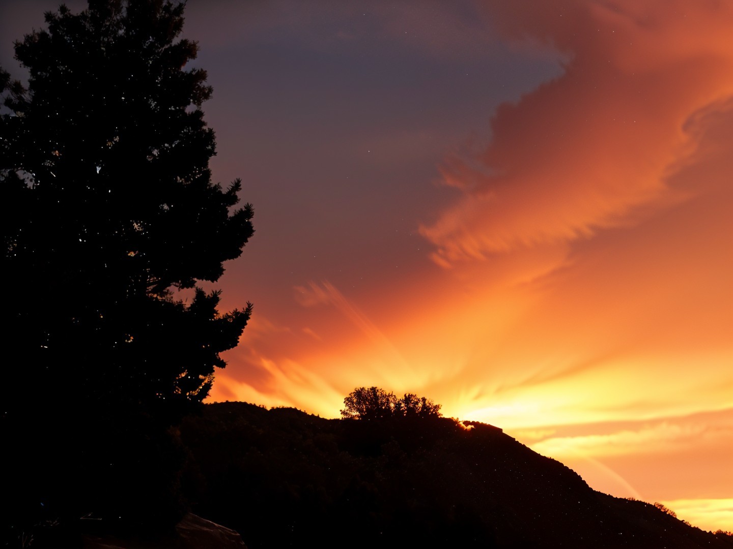 Vibrant Sunset with Silhouetted Tree and Mountains