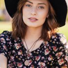 Elegant Woman in Sheer Floral Top and Wide-Brimmed Hat