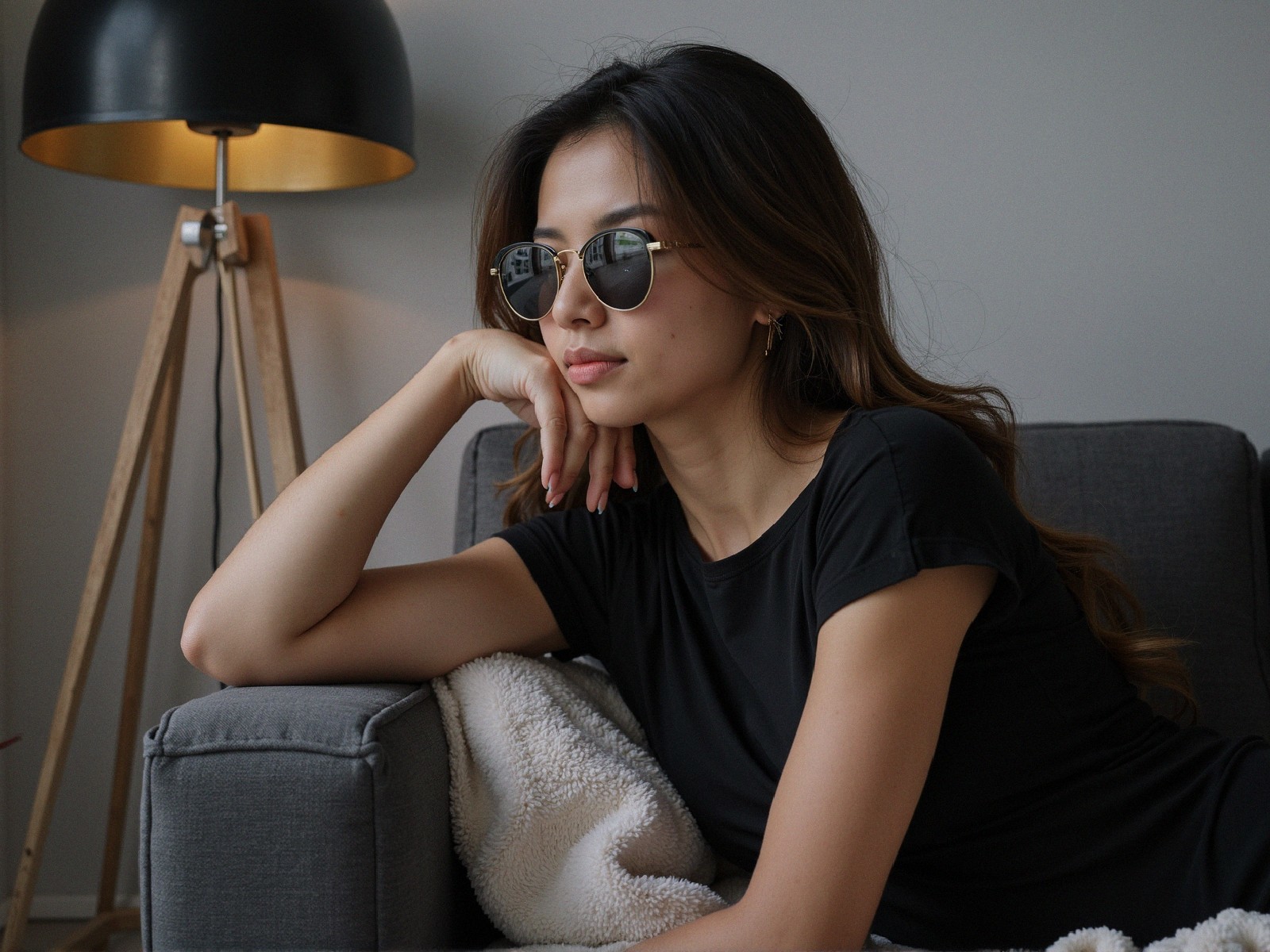 Young woman in round sunglasses on gray sofa