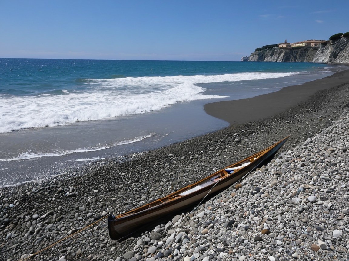 Tranquil Beach Scene with Canoe and Rugged Cliff