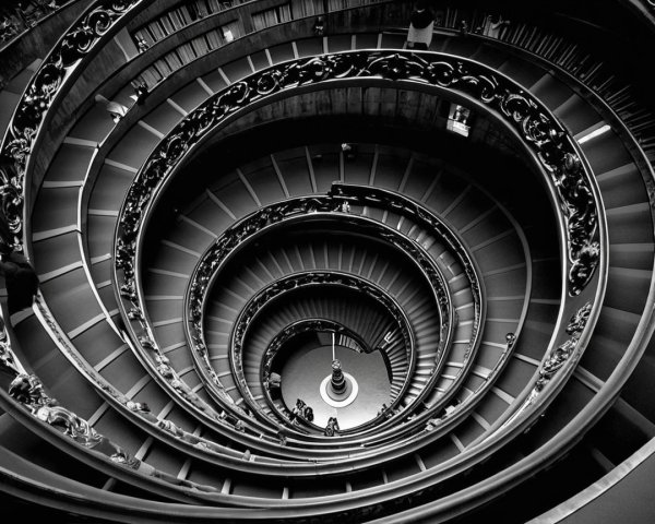 Black-and-white image of a grand spiraling staircase