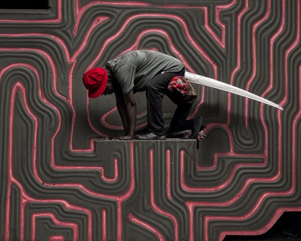 Crouching Figure in Red Hat Against Vibrant Background