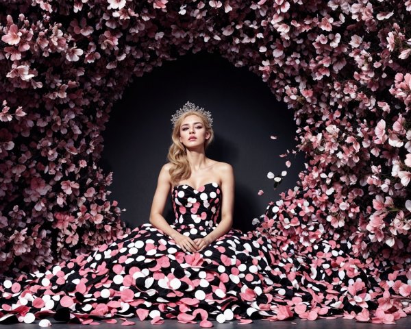 Elegant figure in black gown among vibrant flowers