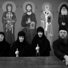 Monochromatic image of people with somber expressions holding religious figures