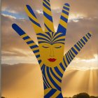 Brightly Colored Hand Sculpture Against Sunset Background