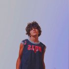 Cosplayer with Silver Hair in Black and Orange Jacket on Cloudy Sky Background