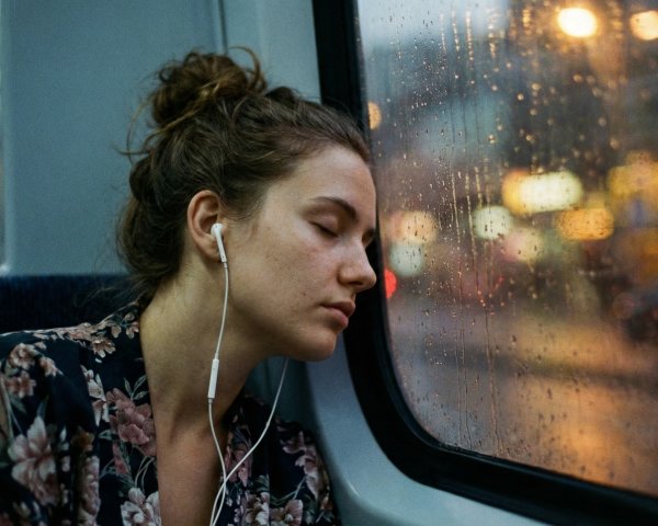 Close-up of a woman sleeping by a rain-covered window