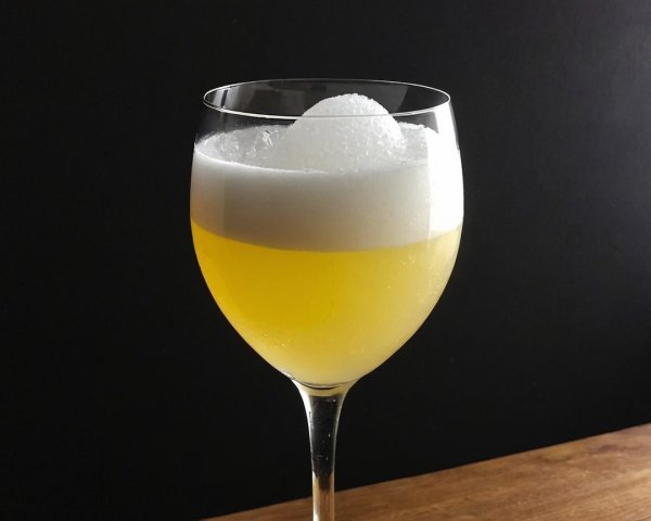 Vibrant Yellow Drink in Elegant Glass on Wooden Surface