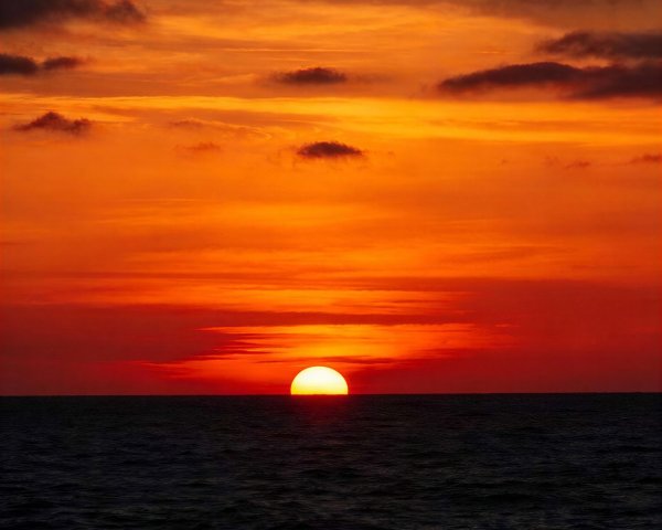Vibrant Sunset Over Dark Ocean with Fiery Sky