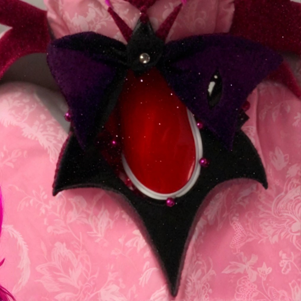 Ornate accessory with bat-wing design and red gem