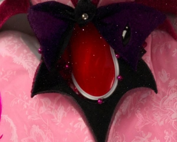 Ornate accessory with bat-wing design and red gem