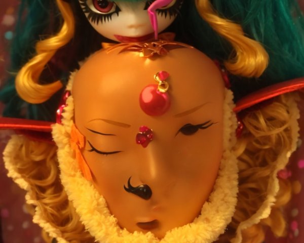 Stylized doll with teal hair and vibrant orange mask