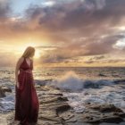Woman in burgundy dress on beach at sunset