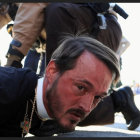 Clerical Figure Restrained by Law Enforcement Officers