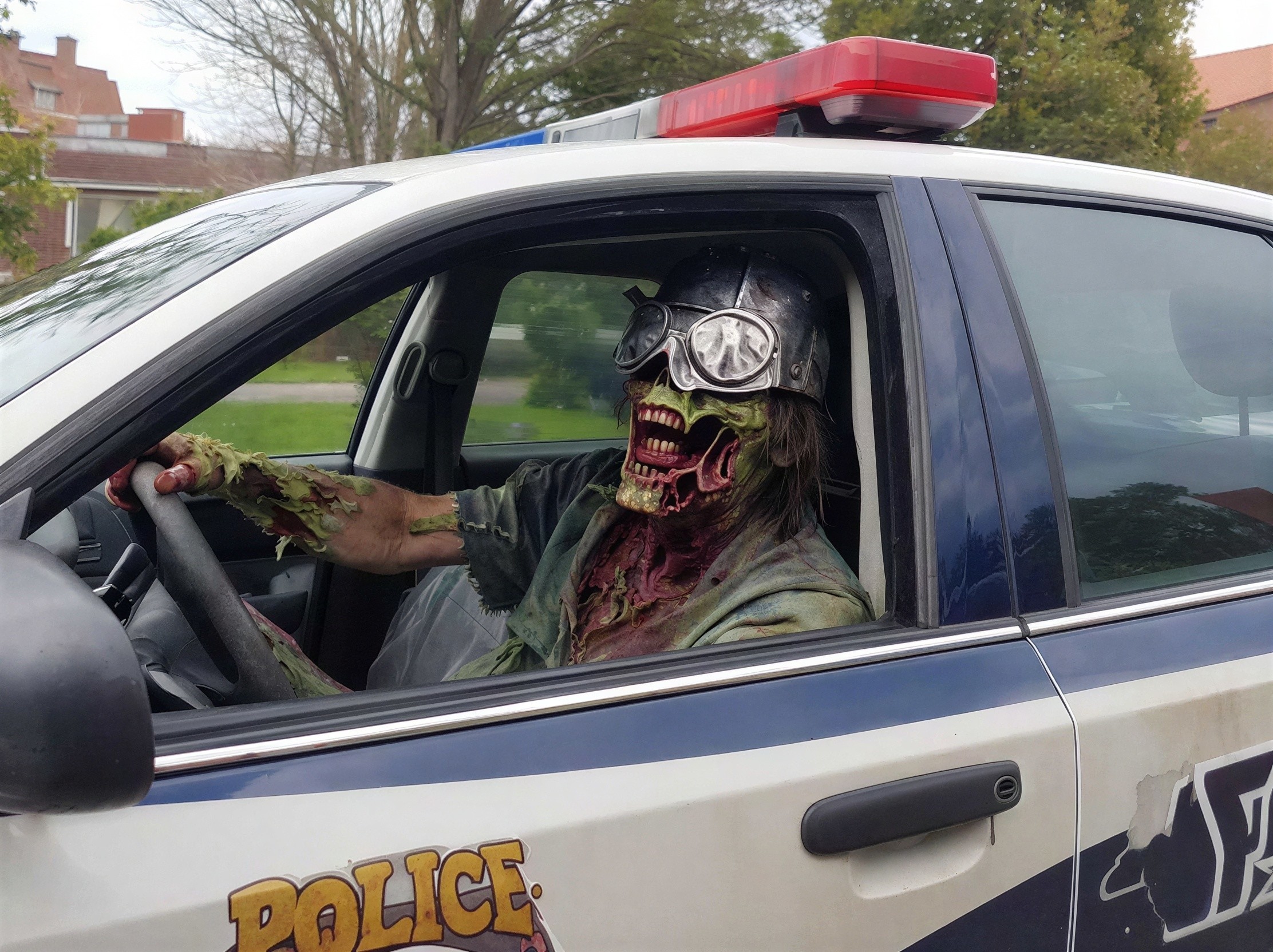 Zombie in Police Car with Distressed Clothing and Goggles