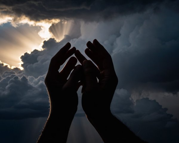 Silhouetted Hands Against Dramatic Cloudy Sky