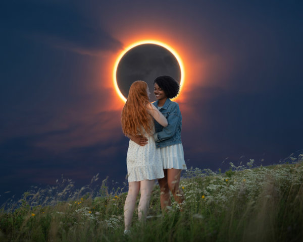 Women Embracing on Hillside During Solar Eclipse
