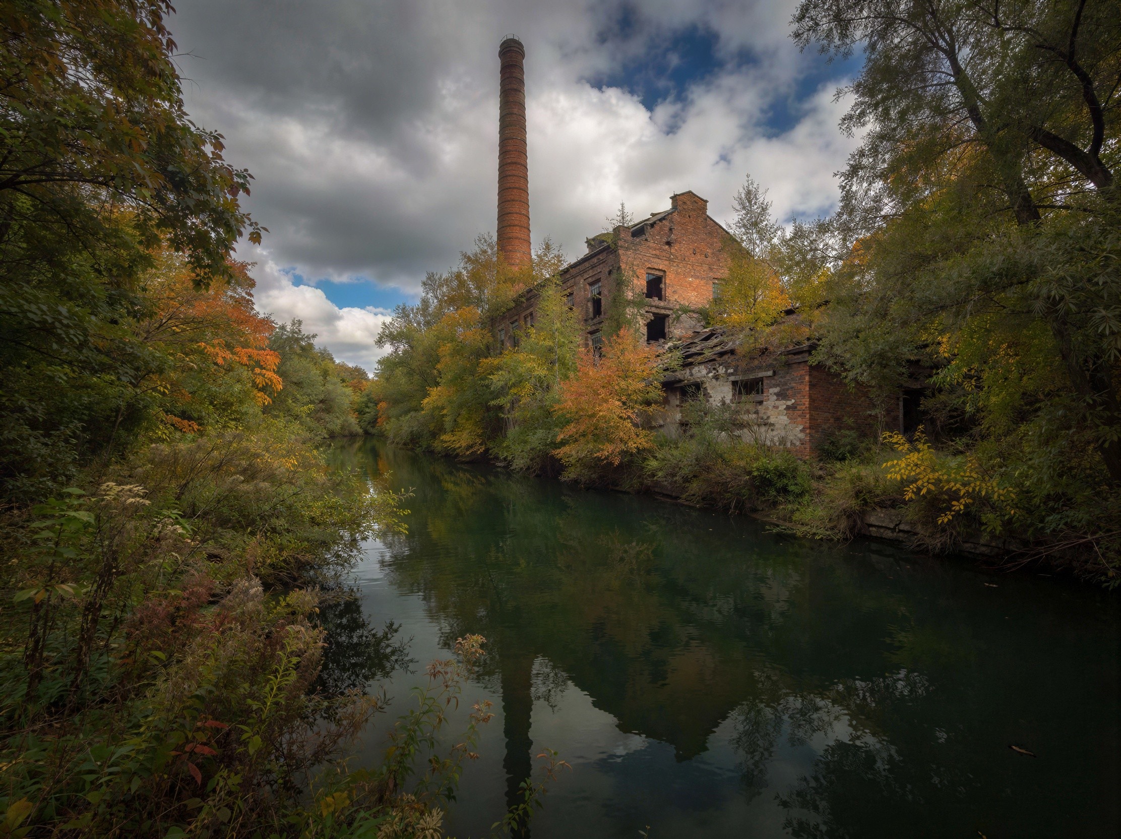 Wide-angle view of a serene river with autumn foliage