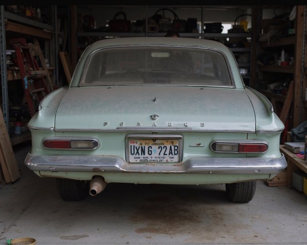 Vintage Light Blue/Green Car in Dusty Garage Setting