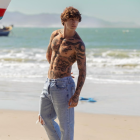 Muscular Man with Sword on Serene Beach Setting