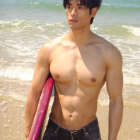 Muscular Man on Beach with Ocean and Blue Sky