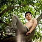 Muscular Young Man with Wings in Lush Foliage Scene