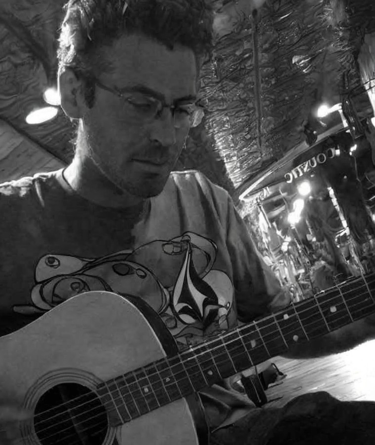 Man Playing Acoustic Guitar in Wooden Room with Neon Sign